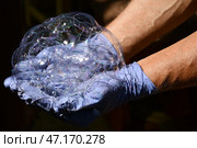 Men's hands in purple vinyl gloves hold soap bubbles on their palms. Sun glare on soap suds. Зыбкая надежда. бережное отношение. Строить воздушные замки. Стоковое фото, фотограф Ольга Солопова / Фотобанк Лори