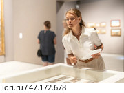 Girl looks at various paintings and drawings at an art exhibition in museum. Стоковое фото, фотограф Яков Филимонов / Фотобанк Лори