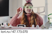 Gamer girl in pink sweater enjoys gaming session with Easter-themed setup. Holding controller, she celebrates victory, feeling festive and energized in cyberpunk-inspired holiday mood. Стоковое видео, видеограф Енваев Андрей / Фотобанк Лори