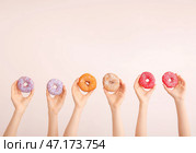Женские руки со сладкими пончиками на цветном фоне. Стоковое фото, фотограф Pixel_shot / Фотобанк Лори