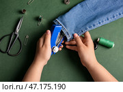 Женские руки с различными принадлежностями для шитья джинс на зеленом фоне. Стоковое фото, фотограф Pixel_shot / Фотобанк Лори