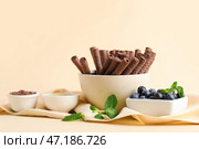 Чаши вкусные шоколадные вафельные трубочки, черника и сгущенное молоко на бежевом фоне. Стоковое фото, фотограф Pixel_shot / Фотобанк Лори
