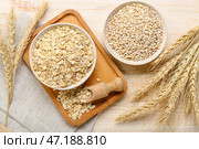 Миски сырой овсянки, перловой крупы и колосков на деревянном фоне. Стоковое фото, фотограф Pixel_shot / Фотобанк Лори
