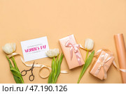 Композиция с подарочными коробками, поздравительной открыткой, оберточной бумагой и цветами тюльпана на цветном фоне. Празднование женского дня. Стоковое фото, фотограф Pixel_shot / Фотобанк Лори