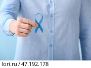 Человек с голубой лентой на цветном фоне, крупным планом. Концепция осведомленности о раке простаты. Стоковое фото, фотограф Pixel_shot / Фотобанк Лори