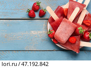 Тарелка с милыми клубничными морожеными-пломбиром на голубом деревянном фоне. Стоковое фото, фотограф Pixel_shot / Фотобанк Лори