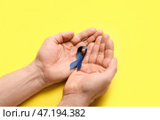 Мужские руки с голубой лентой на цветном фоне. Концепция рака толстой кишки. Стоковое фото, фотограф Pixel_shot / Фотобанк Лори