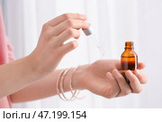 Женщина наносит эфирное масло на руку на светлом фоне, крупным планом. Стоковое фото, фотограф Pixel_shot / Фотобанк Лори