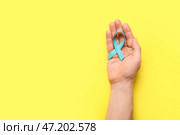 Мужская рука с голубой лентой на цветном фоне. Концепция рака простаты. Стоковое фото, фотограф Pixel_shot / Фотобанк Лори
