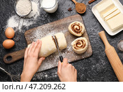 Женщина готовит булочки с корицей на черном фоне. Стоковое фото, фотограф Pixel_shot / Фотобанк Лори