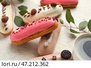Вкусные глазированные эклеры и эвкалипт на светлом фоне. Стоковое фото, фотограф Pixel_shot / Фотобанк Лори