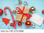 Подарочная коробка с елочными шарами, конвертом и карамельной тростью на синем фоне. Стоковое фото, фотограф Pixel_shot / Фотобанк Лори