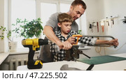 Guides for son through hands-on tasks, father encouraging skill-building. Skills developed in workshop, with attention to detail and safety, as father passes down practical knowledge and skills. Стоковое видео, видеограф Енваев Андрей / Фотобанк Лори