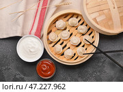 Пароварка с вкусными варениками и соусами на темном фоне. Стоковое фото, фотограф Pixel_shot / Фотобанк Лори