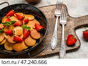 Деревянная доска со сковородкой с мини-блинами и клубникой на столе. Стоковое фото, фотограф Pixel_shot / Фотобанк Лори