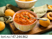 Деревянная доска с миской вкусного абрикосового варенья на зеленом фоне, крупным планом. Стоковое фото, фотограф Pixel_shot / Фотобанк Лори