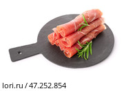 Грифельная доска с ломтиками вкусной ветчины и розмарином на белом фоне. Стоковое фото, фотограф Pixel_shot / Фотобанк Лори