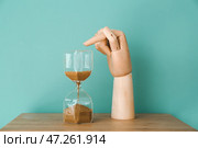 Деревянная рука, указывающая на песочные часы на столе. Стоковое фото, фотограф Pixel_shot / Фотобанк Лори
