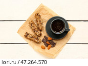 Пергамент с вкусным печеньем бискотти, чашкой кофе, миндалем и шоколадом на белом деревянном фоне. Стоковое фото, фотограф Pixel_shot / Фотобанк Лори