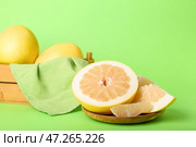 Тарелка с половинками помело, ломтиком и корзиной целых фруктов на зеленом фоне. Стоковое фото, фотограф Pixel_shot / Фотобанк Лори