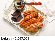 Поднос с вкусными эклерами, шоколадом и джезвой кофе на светлом фоне. Стоковое фото, фотограф Pixel_shot / Фотобанк Лори