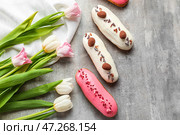 Вкусные глазированные эклеры и тюльпаны на сером столе. Стоковое фото, фотограф Pixel_shot / Фотобанк Лори