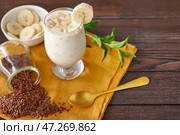 Стакан йогурта с бананом и семенами льна на деревянном фоне. Стоковое фото, фотограф Pixel_shot / Фотобанк Лори