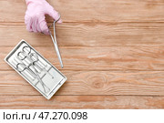 Рука хирурга с инструментами на деревянном фоне. Стоковое фото, фотограф Pixel_shot / Фотобанк Лори