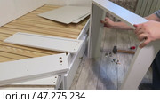 The man is assembling pull-out shelves for the sofa bed from wooden panels. He connects them with furniture hardware. Стоковое видео, видеограф Vadzim Yakubovich / Фотобанк Лори