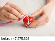 Женские руки с красным сердцем и стетоскоп на белом фоне деревянные. Кардиологическая концепция. Стоковое фото, фотограф Pixel_shot / Фотобанк Лори
