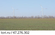 Wind turbines spin energetically against a blue sky, harnessing renewable energy in the countryside field on spring. Supporting farmers through innovative practices. Green and renewable power concept. Стоковое видео, видеограф Ирина Михайличенко / Фотобанк Лори