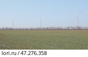 Wind turbines spin energetically against a blue sky, harnessing renewable energy in the countryside field on spring. Supporting farmers through innovative practices. Green and renewable power concept. Стоковое видео, видеограф Ирина Михайличенко / Фотобанк Лори