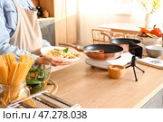 Молодая женщина с вкусной пастой записывает видеоурок на кухне. Стоковое фото, фотограф Pixel_shot / Фотобанк Лори