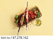Деревянная доска с вкусным хамоном, специями и миской масла на цветном фоне. Стоковое фото, фотограф Pixel_shot / Фотобанк Лори