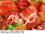 Деревянная доска с ломтиками вкусного хамона, крупным планом. Стоковое фото, фотограф Pixel_shot / Фотобанк Лори