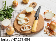 Доска с нарезанным луком и ножом на светлом деревянном фоне, крупным планом. Стоковое фото, фотограф Pixel_shot / Фотобанк Лори