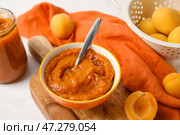 Деревянная доска с миской вкусного абрикосового варенья на светлом фоне, крупным планом. Стоковое фото, фотограф Pixel_shot / Фотобанк Лори
