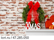 Рождественский венок и слово XMAS на каминной полке возле кирпичной стены. Стоковое фото, фотограф Pixel_shot / Фотобанк Лори
