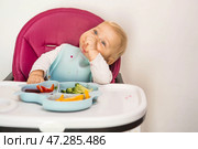 Baby food. The first meal. Feeding the baby. A cute little kid eats vegetables. Healthy food. The child is sitting on a high chair for feeding. Fresh vegetables and fruits. Стоковое фото, фотограф Photojuli / Фотобанк Лори