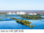 Широакя река Замбези с островами на границе Замбии и Зимбабве и водяная пыль от водопада Виктория на горизонте, вид сверху с вертолёта (2014 год). Стоковое фото, фотограф Анна Ефимова / Фотобанк Лори