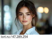 A young girl with delicate facial features, brown eyes and a natural blush. Her skin is smooth, and light freckles add naturalness and charm. Her hair is slightly tousled, styled in a casual hairstyle with loose strands. She is dressed in a white shirt, which emphasizes the minimalist style. The background is blurred, creating a soft, warm atmosphere with cozy lighting. Her gaze is calm and penetrating, and her facial expression radiates confidence and harmony. Стоковое AI-изображение, AI-художник Анна Кривицкая / Фотобанк Лори