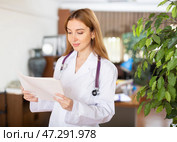Young female therapist is studying important documents while standing in the office. Стоковое фото, фотограф Яков Филимонов / Фотобанк Лори