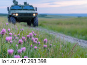 Military vehicle on the background of a green steppe with flowers. Стоковое AI-изображение, AI-художник Евгений Харитонов / Фотобанк Лори