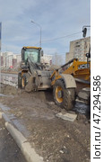 ANGARSK, IRKUTSK REGION, RUSSIA - March 20, 2025: Vertical video of spring cleaning of city roads. Road workers use excavators and loaders to collect icy mud from the road in a bucket and remove it. Редакционное видео, видеограф Виктория Катьянова / Фотобанк Лори