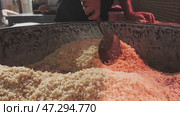 The chef stirs steaming rice in a large pilaf cauldron with a slotted spoon. Стоковое видео, видеограф Aleksey Kidisyuk / Фотобанк Лори