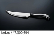 Sleek stainless steel knife resting on a dark surface, emphasizing its sharpness and design for culinary tasks. Стоковое AI-изображение, AI-художник Сергей Толмачёв / Фотобанк Лори