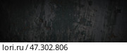 Dark wide panoramic background. Peeling paint on a concrete wall. Dark grunge texture of old cracked flaking paint. Weathered rough painted surface. Patterns of cracks. Darkness background for design. Стоковое фото, фотограф Андрей Степанов / Фотобанк Лори