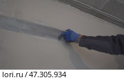 Alignment of the walls near the ceiling. Home improvement. Apartment renovation. Men's hands in protective gloves with a construction metal rule in their hands, Стоковое видео, видеограф Darya Komarova / Фотобанк Лори