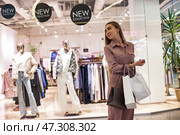 Woman Exploring Shopping Mall With Bags in Hand, Surrounded by Vibrant New Fashion Collections. Стоковое фото, фотограф Aleksandr Golubev / Фотобанк Лори