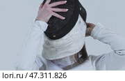 Young woman fencer in white suit puts on her helmet. Стоковое видео, видеограф Константин Шишкин / Фотобанк Лори